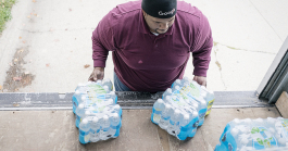 William Harris, 31, of Flint, slides two cases of water off the back of his team's delivery truck on Flint's eastside. The team from Asbury United Methodist deliver water to 60 to 70 homes on their route.