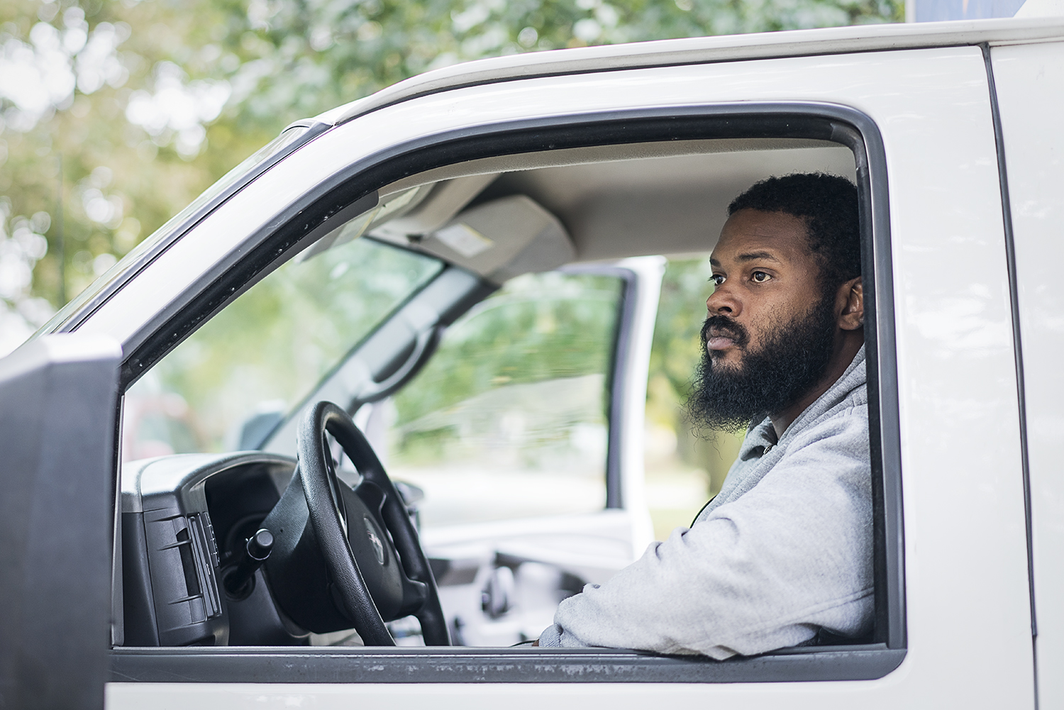 Flint resident Alan Lee, 32, waits as his team makes a delivery to a home in Flint's 4th Ward. "It's a cool job to do," he says. "You get to give to people in the community."