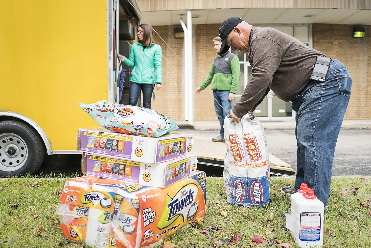 Retired police officer Steven Moore, 52, of Davison prepares to heft two bags of charcoal briquettes onto his shoulder and carry them into the trailer in the parking lot of the Riverside Tabernacle Church before heading to the riverfront for the Flin