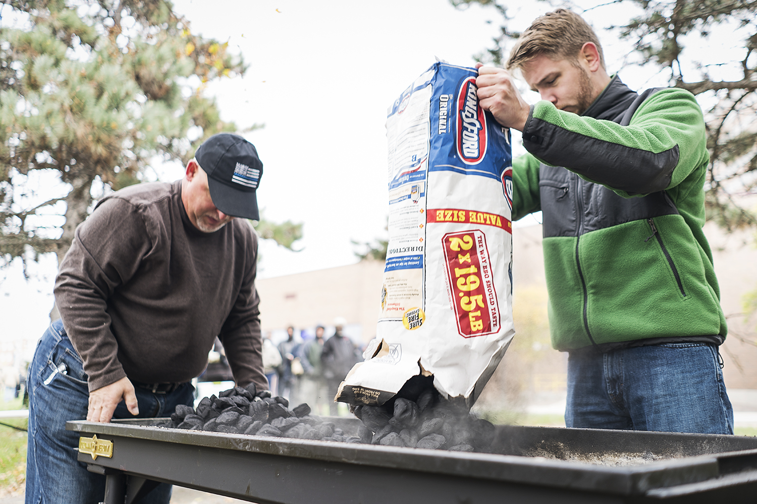 Volunteers Steven Moore, 52 (left) of Davison, and Steven Elkins, 27, of Flint, prepare the grill at Riverbank Park for the Flint Community Cookout. They generally grill 300 burgers and more than 100 hot dogs at each cookout. 