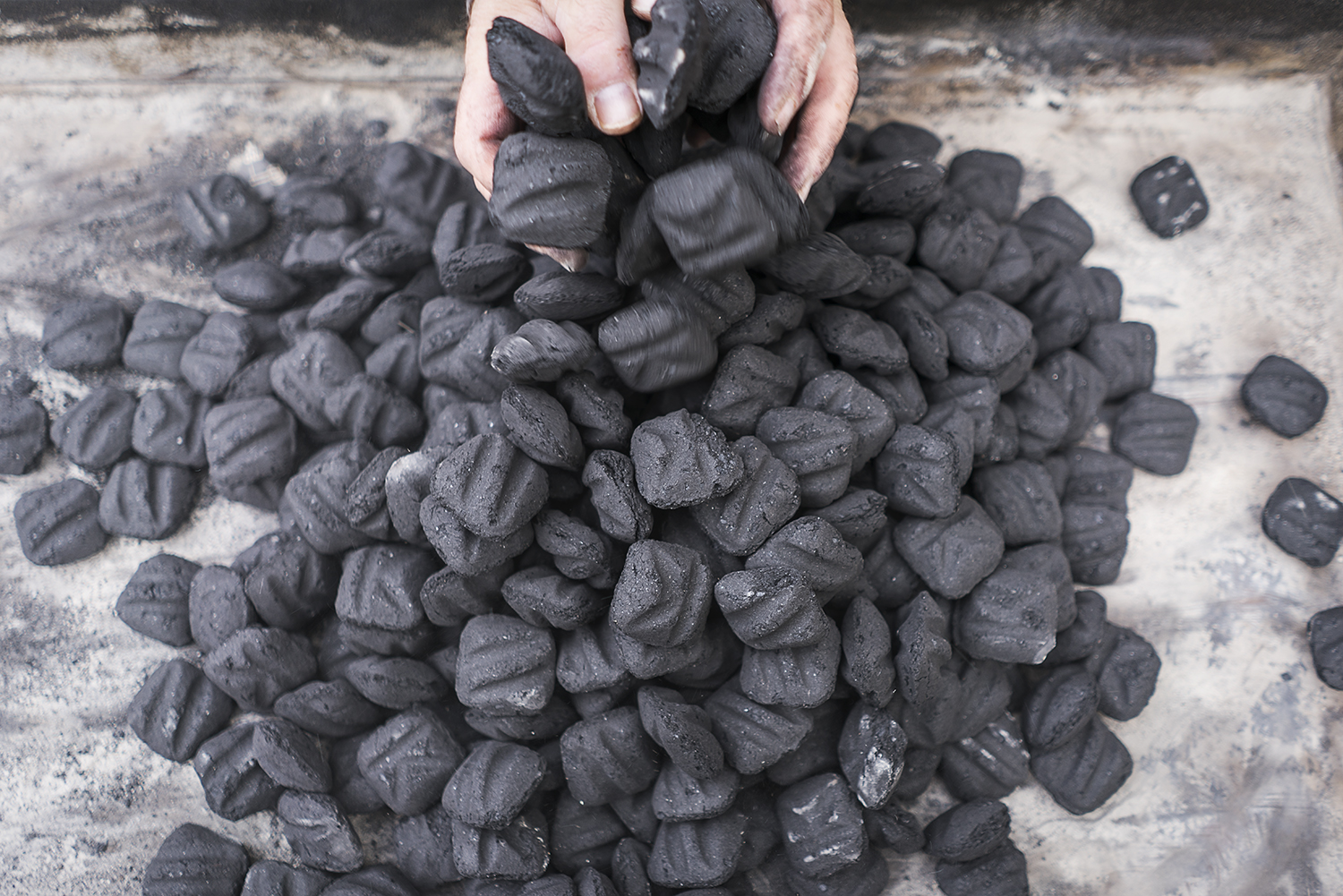 Volunteer and Davison resident Steven Moore, 52, organizes a pile of charcoal briquettes in the grill at the Flint Community Cookout. 