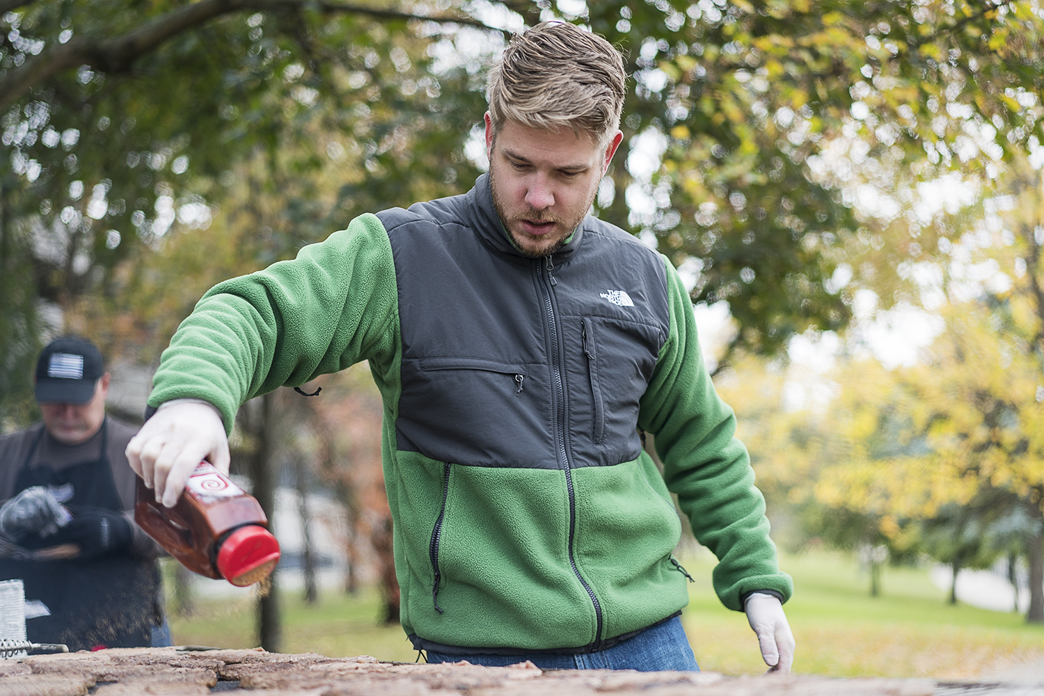 Flint resident Steven Elkins, 27, seasons dozens of burgers as they cook on the grill at the Flint Community Cookout at the Riverbank Park. One of Elkins' goals for the cookout is to make sure that it feels like a family barbecue, not a feeding line.