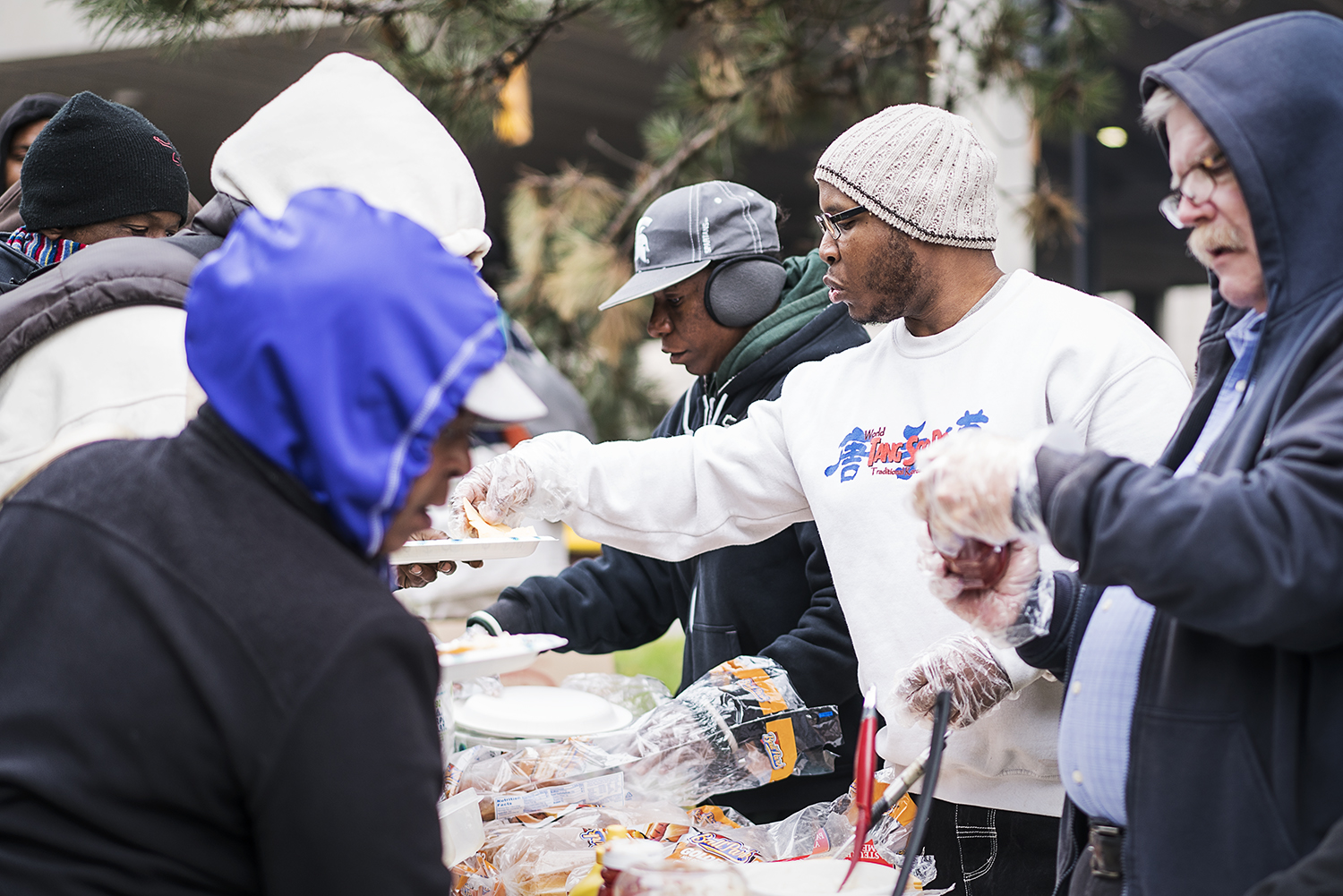 Burton resident Paul C. Owens, 31, (center) serves up some food at the Flint Community Cookout at the Riverbank Park. Owens, a volunteer for 4 years, uses the cookouts as an opportunity to "do the Lord's work" and to meet people, overcoming his self-