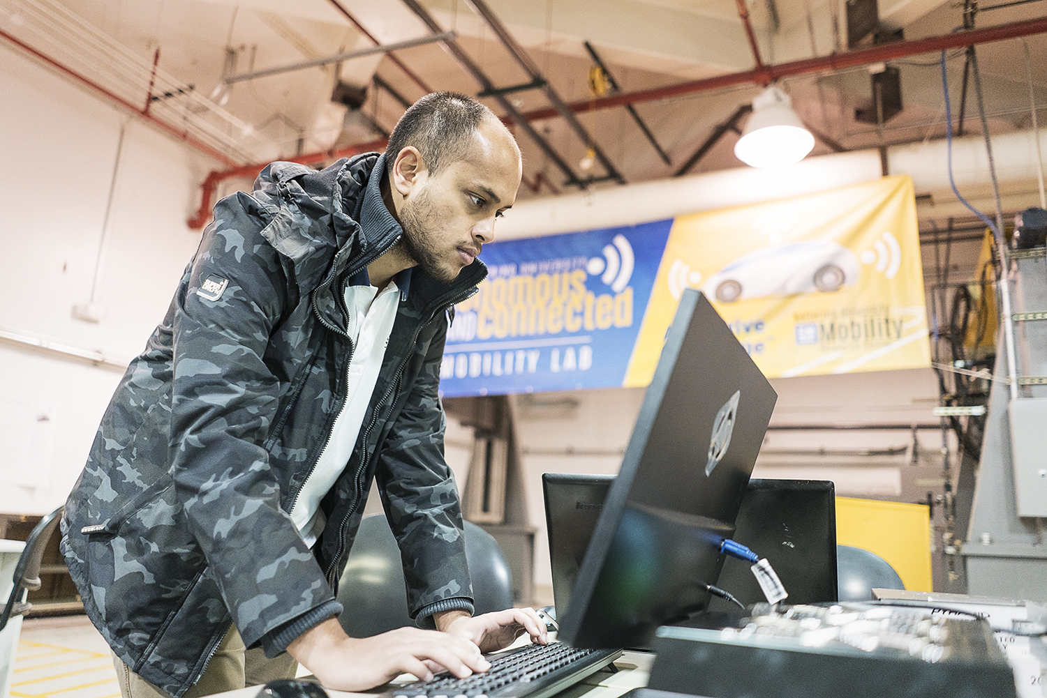 Flint, MI - Friday, November 10, 2017: Shobit Sharma, 26, one of two student coordinators for the SAE/GM AutoDrive Competition checks a connection between the server and Chevrolet Bolt electronic car in the garage at Kettering University.