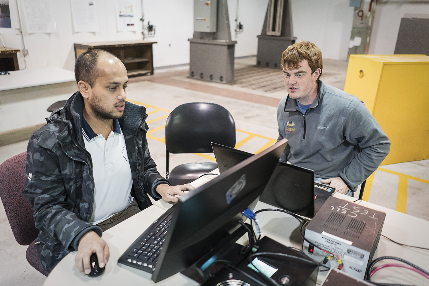 Flint, MI - Friday, November 10, 2017: Project coordinators Shobit Sharma, 26 (left), and Alex Rath, 22, verify the connection between the server and Chevrolet Bolt in the garage at Kettering University that is being used to house the vehicle for the