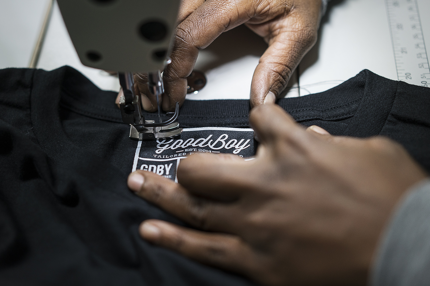 GoodBoy Clothing textile expert Tameka Davis, 37, of Flint, stitches tags into new shirts that are headed to the showroom at the new GoodBoy Clothing storefront in downtown Flint.