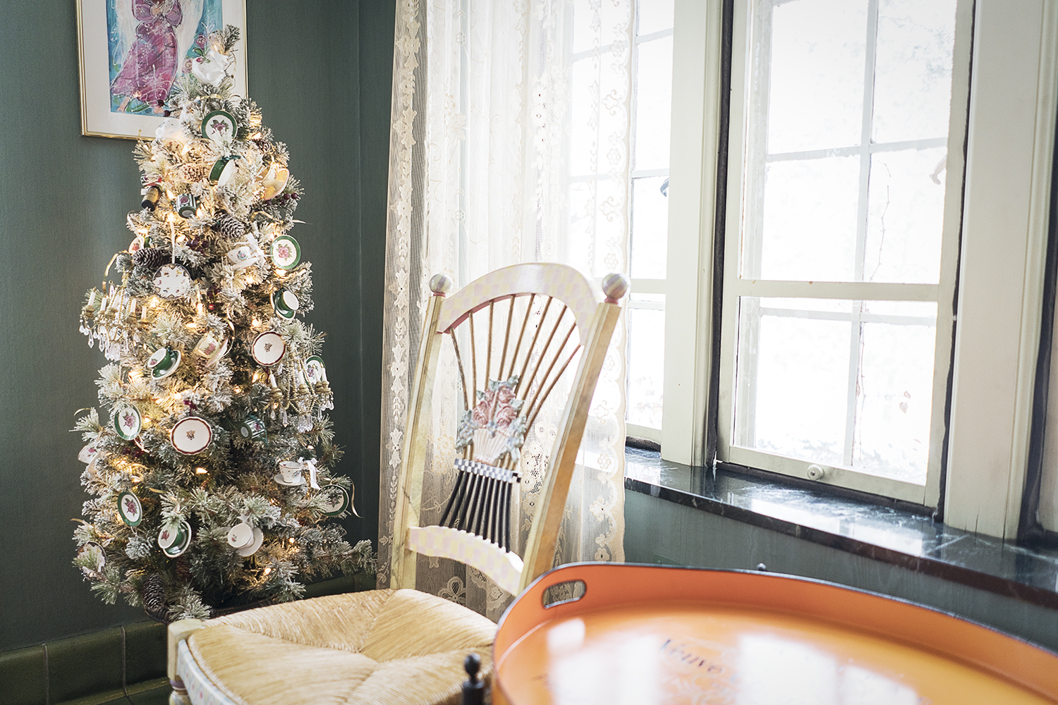 A small Christmas tree decorated with miniature tea cups and saucers sits in the corner of a room in the Heddy home.