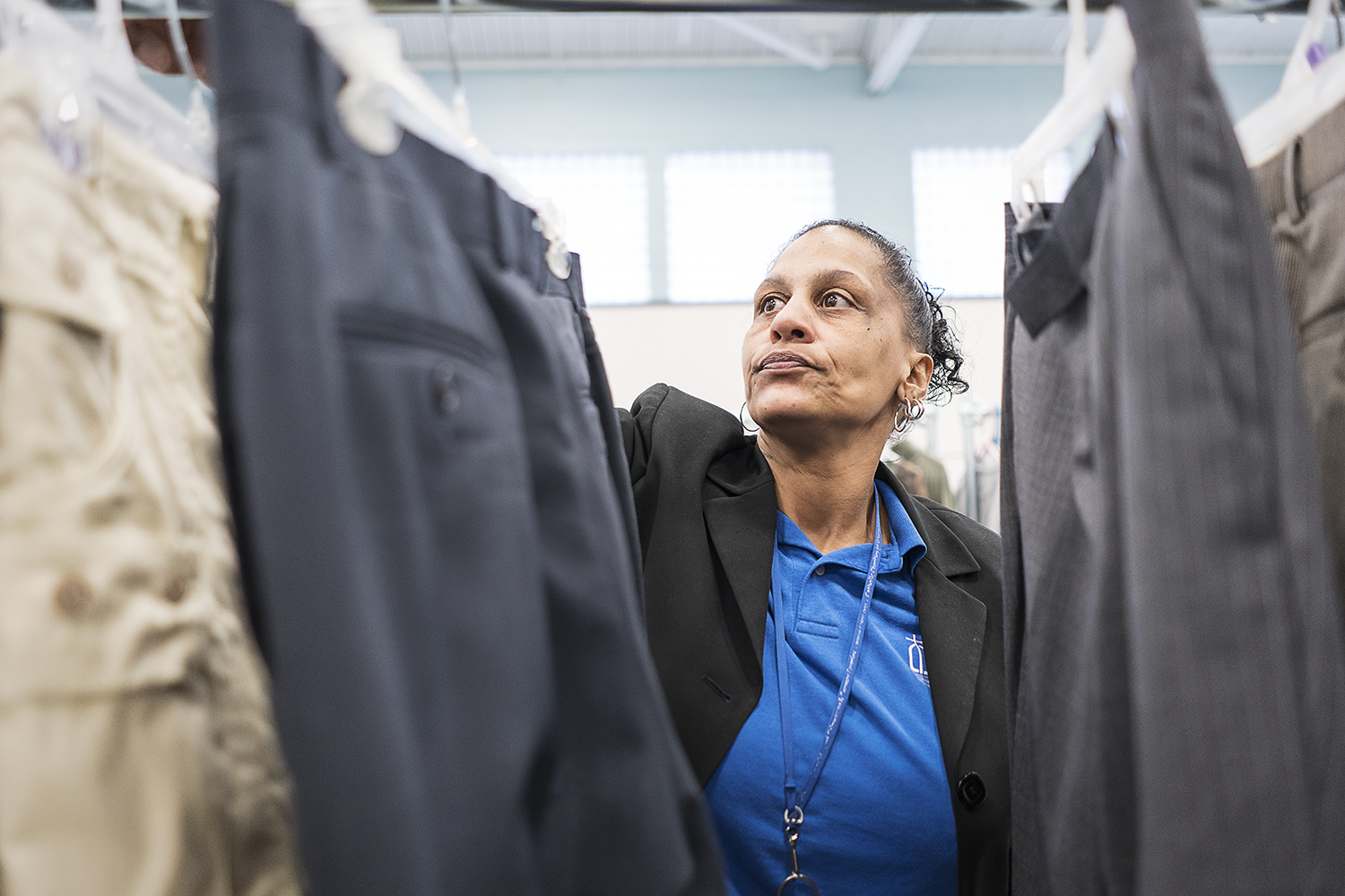 Community Closet Coordinator at the Catholic Charities Center for Hope Redonna Riggs, 47, of Flint, organizes donated clothing hanging from a clothing rack.