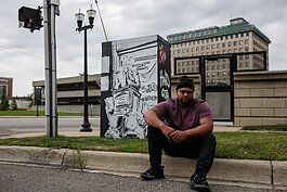 Keyon Lovett, the ArtSchool Dropout, sits in front of an electrical box he was commissioned to design downtown Flint.