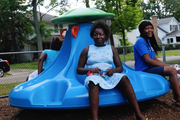 Civic Park residents Ceterra Williams (middle), Mariah Fisher (right), and Natalia Williams enjoy the spin of the new Bassett Park merry-go-round.