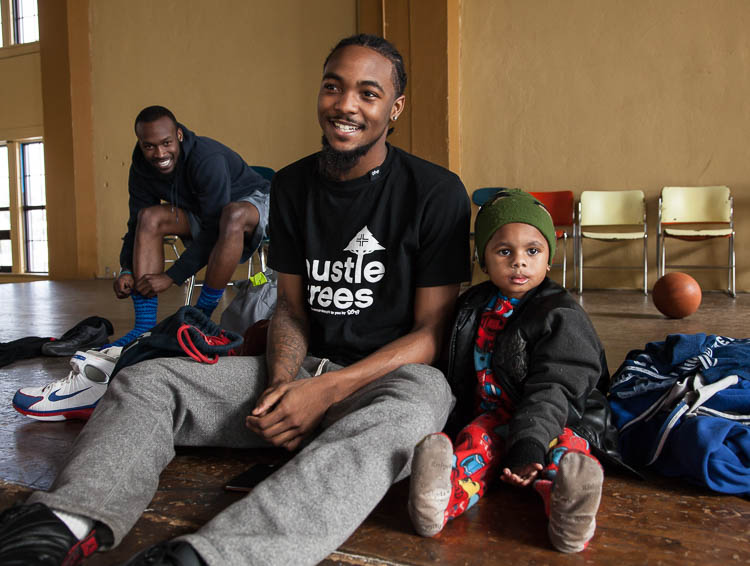 D.J. Dye, 3, of Flint sits with Simeun McGee, 21, of Flint on the stage in the gym at Berston Field House in Flint. D.J. was there with his father Troy George, 23, of Flint who was in the basketball game at that moment. At left is Quavon Trawick. 