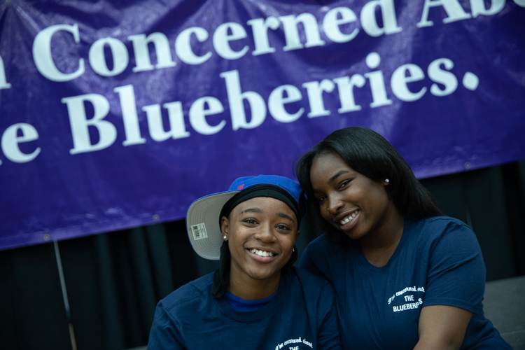 Blueberry Ambassadors pose in front of a recreation of the billboard sign that started the Blueberry Movement in 2013.
