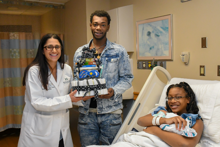 Dr. Mona Hanna-Attisha presents the 1,000th 'Born to Read' bundle to Melody, the daughter of Joy McGee and Delon McGowan, on Dec. 7, 2018.