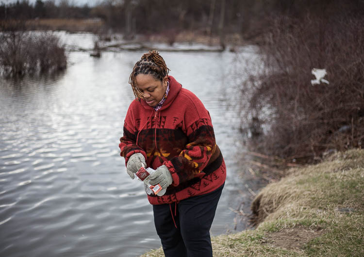 Carma Lewis picks up trash along the lake in Flint Park during a visit.