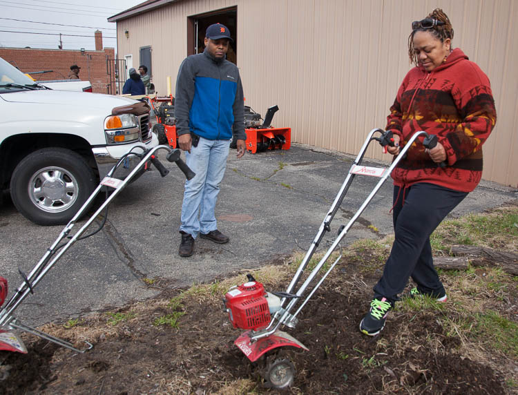 Carma Lewis makes herself familiar with a small rototiller at the Community Tool Shed at the Neighborhood Engagement Hub on Martin Luther King Avenue. At left is Ceasare Copeny, assistant manager of the Community Tool Shed.
