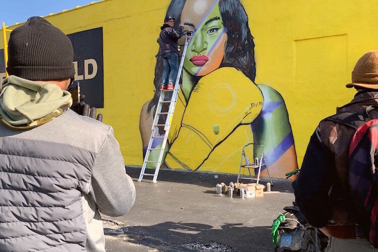 Local muralist Charlie Boike painting a mural of Claressa Shields on the side of Julie's Pawn shop on 2820 South Saginaw for Flint's Free City Mural Festival on Saturday, October 12.