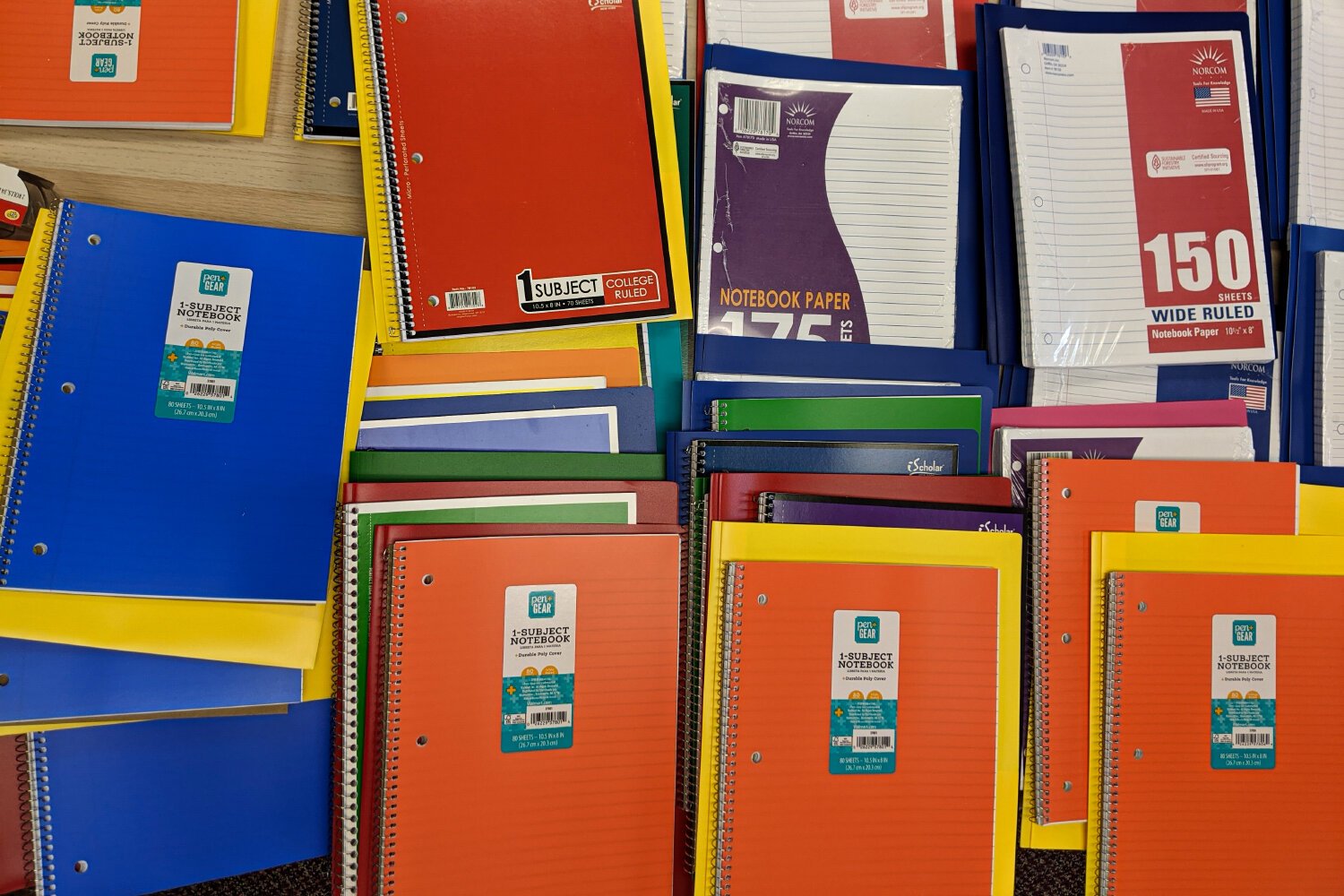 In the middel of the room sits a table covered with colorful college-ruled notebooks.