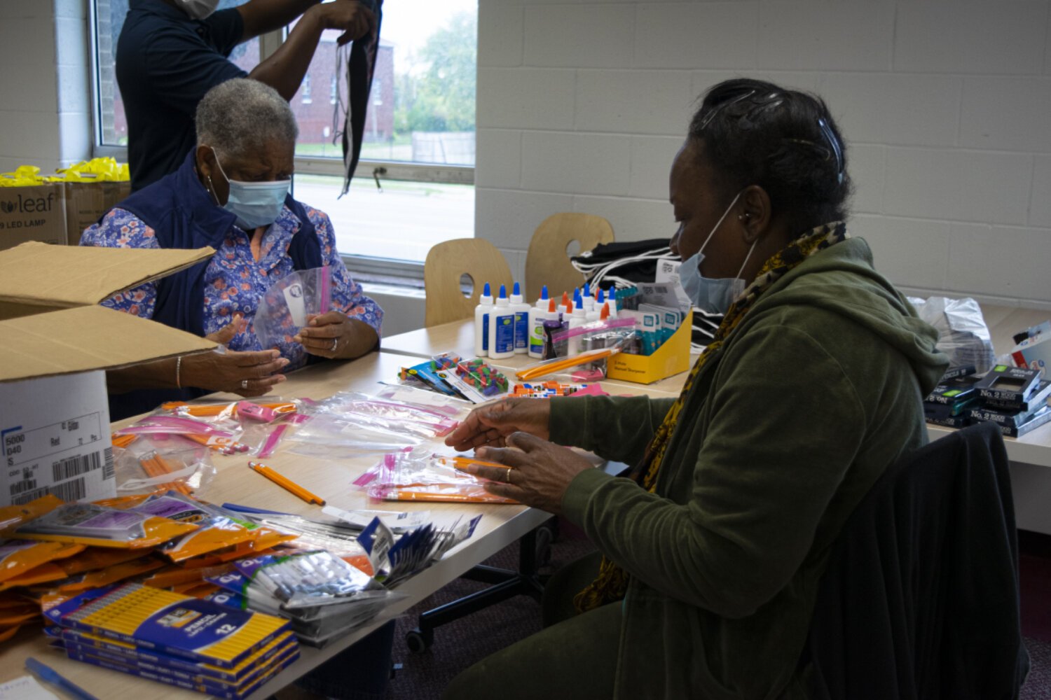 Fredricka Gist (left) and Nancy Kimble (right), both BHNA members, organize school supplies to go in the children's bags.