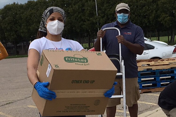 Jessica Robinson, director of Flint Community School Corps, and Rawlan Lillard, program manager for Community Schools, helping with a food delivery as part of the Flint Community Education Initiative.