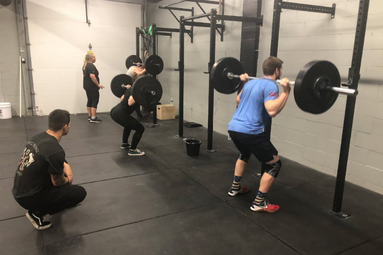 Jake Saldana looks on as clients lift at Flint CrossFit.