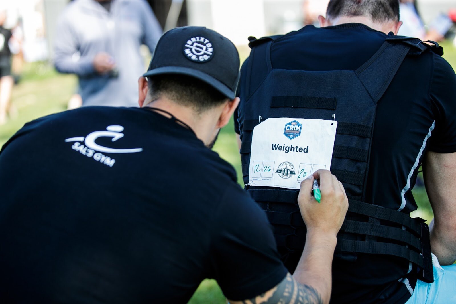 Sal's Gym co-owner Jake Saldaña marks finals scores on the bib of a race participant for the CrossFlint 5K Challenge during the 45th annual Crim Festival of Races in downtown Flint.