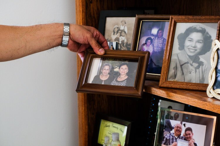 icky Reyes holds a picture of his mother and sister from a shelf filled with family photos. His mother now lives in Grand Blanc.