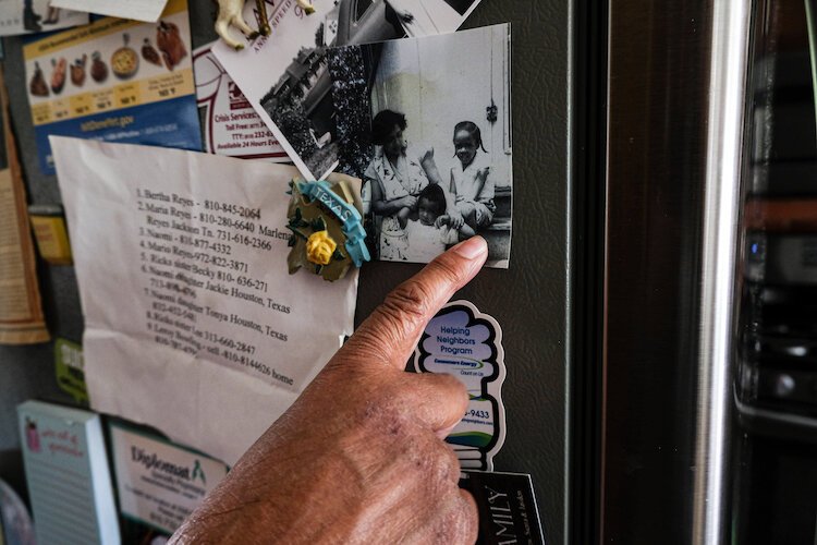 Amongst refrigerator flyers and her neighborhood contacts, Speed points to an older photograph herself seated alongside her mother and younger brother.