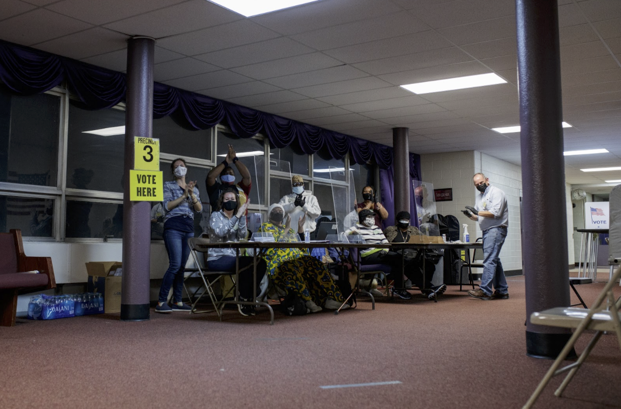 Shakeeta Brooks and other poll volunteers, at Cathedral of Faith Church, applaud voters as they complete their ballots.