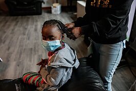 Chanelle Hodo, 26, a resident of Shelter of Flint, beads her daughter's hair.