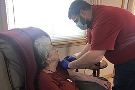 Nathaniel Bergman administers a COVID-19 vaccine to a homebound resident in her home.