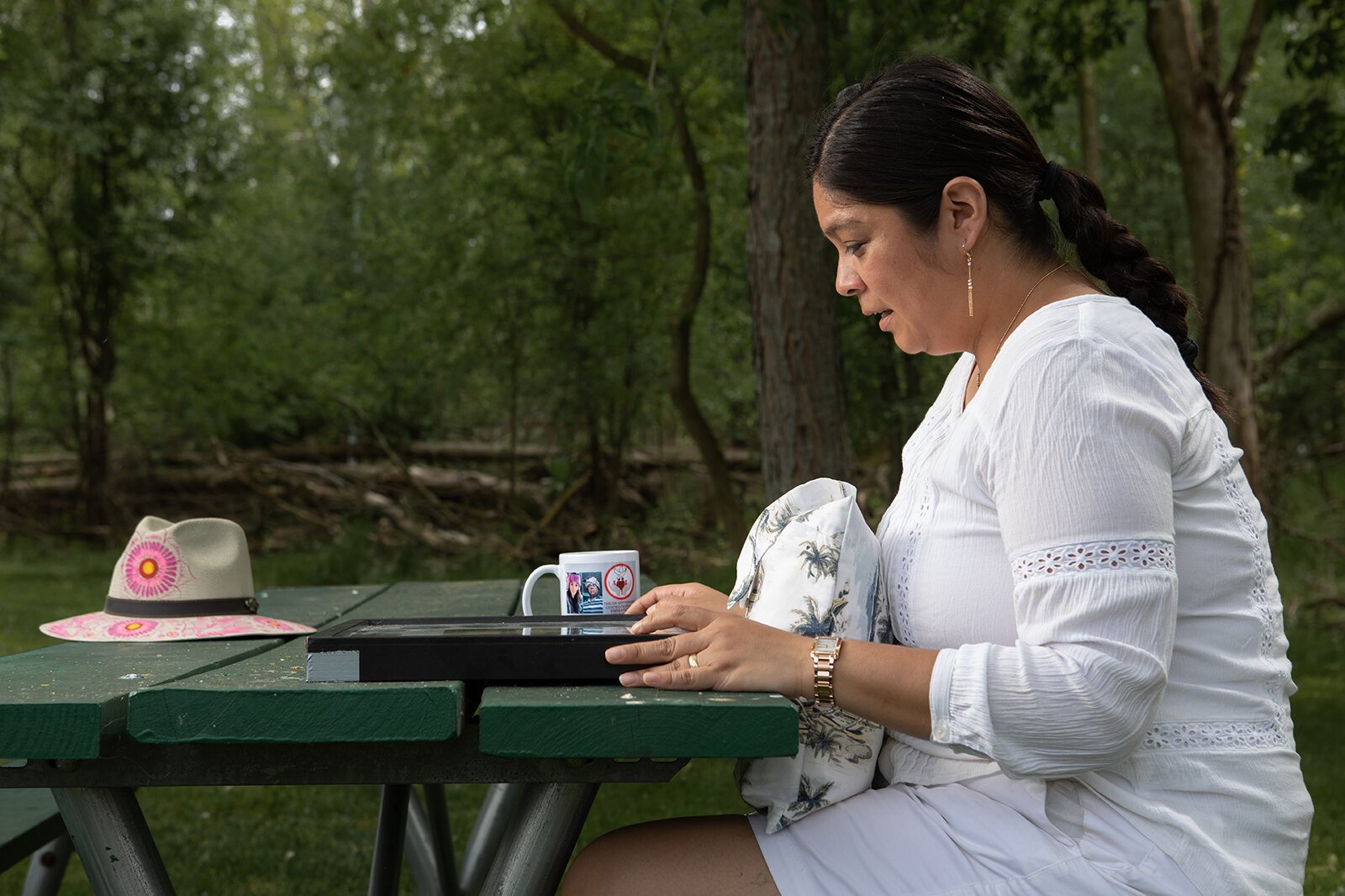 Isabel Romero looks at mementos of her family members who have died of COVID-19.