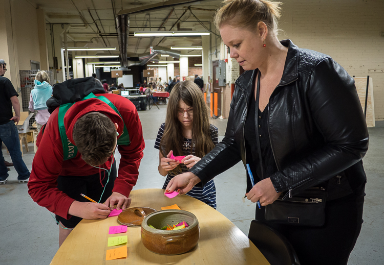 Alisha Sidebottom of Fenton (right) as well as Gabriel Wright, 14, and her sister Aurora Wright, 11, both of Flint, vote for their favorite presenter at Flint SOUP during the October event at Factory Two in Flint. All votes were collected in the "tac