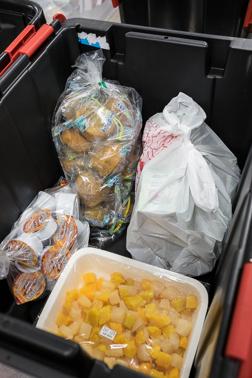 A crate is loaded with food that will be delivered to a site that will divide and serve the food.