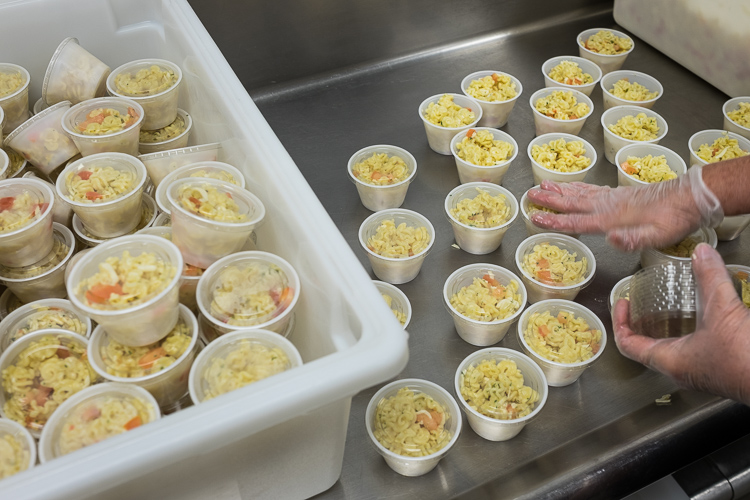 Cups of pasta salad are prepared in the production kitchen at the Food Bank of Eastern Michigan in Flint.