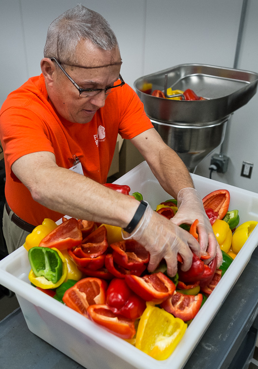 Scott Smith, a culinary site monitor, loads peppers into a slicer in the production kitchen at the Food Bank of Eastern Michigan in Flint.