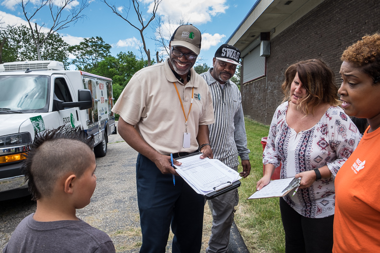 Samuel Berry Sr. (left) and Marquetta Smith (far right) talk to a boy seeking a meal for his grandmother at the Beecher-Vera B. Rison Library in Mt. Morris Township after distributing meals to children in a summer program there.