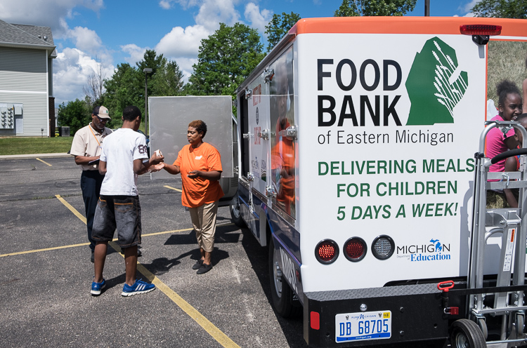 Individually prepared meals are distributed by Samuel Berry Sr. (left) and Marquetta Smith at the Bristol Place Apartments in Mt. Morris Township.