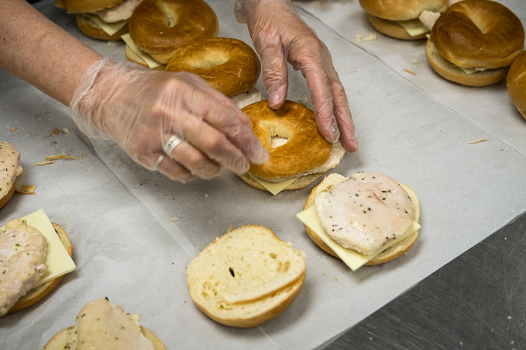 Some of the 700 chicken breast and cheese on bagel sandwiches being prepared in the production kitchen at the Food Bank of Eastern Michigan in Flint.