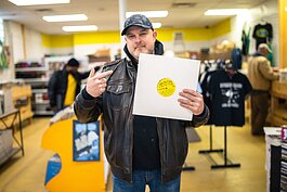 Flint hip-hop artist/DJ Brady Gozza stands holding a Jake the Flake vinyl record inside Jack's Record Stache in downtown Flint.