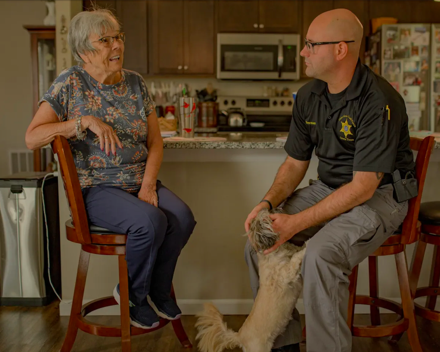 Genesee County Sheriff's Deputy Christian Bowman, of the GRACE Team, visits Pat Kain, a Grand Blanc resident that he helped after she'd been receiving phone calls from an individual posing as a federal agent, at her home on Wednesday, Aug. 30, 2023.