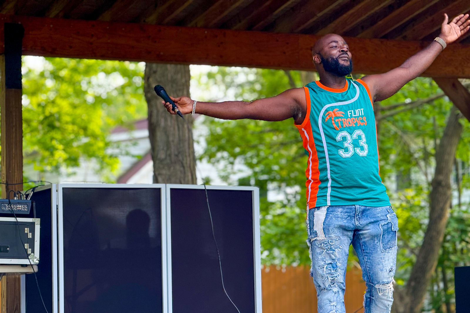 Flint artist and now community organizer G-S tha DreaM stands with his arms wide open during his closing performance at a Juneteenth festival on June 8, 2025.