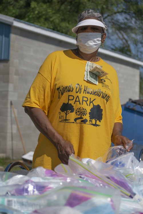 Bonnie Grass stands behind a table handing out feminine hygiene products. Throughout the day, community members gave her money as a birthday present which she clipped on to her shirt.