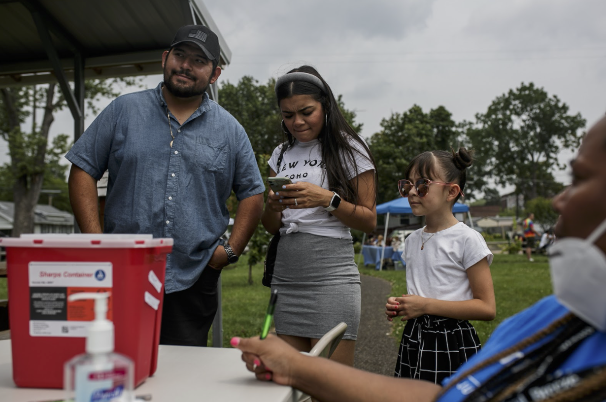 A family talks with Michigan United health workers during a vaccine and health clinic in Eastside Franklin Park on July 24.