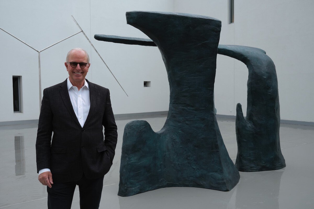 Flint Institute of Arts executive director John Henry standing in front of 'Paradise' in the FIA's Hurand Sculpture Courtyard.
