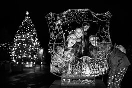 Guests at Applewood smile together for a picture next to an outdoor ice sculpture during the College Cultural area’s 37th Annual Holiday Walk in Flint on Tuesday, Dec. 6, 2022.