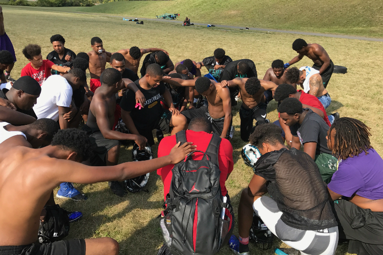 Flint schools head football coach Chris Wilson says a prayer with his team at practice on Thursday, a day before the Jags first home game at Houston Stadium.