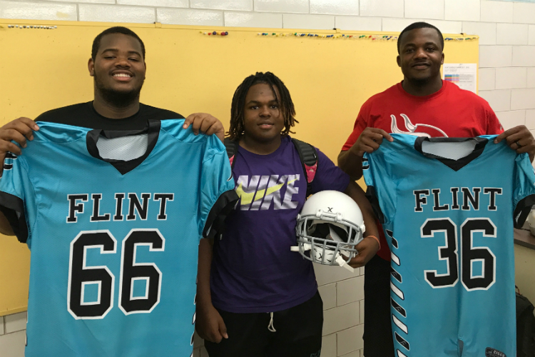 Senior players Kalen Sawyer (left to right) and Jason Miller pose with head football coach Chris Wilson, center, before tomorrow's game against Bay City Western.