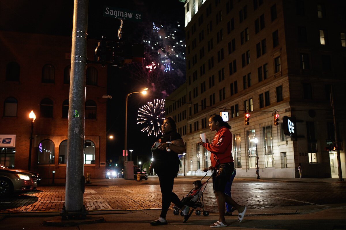 Fireworks go off overhead as people walk downtown Flint on Juneteenth.
