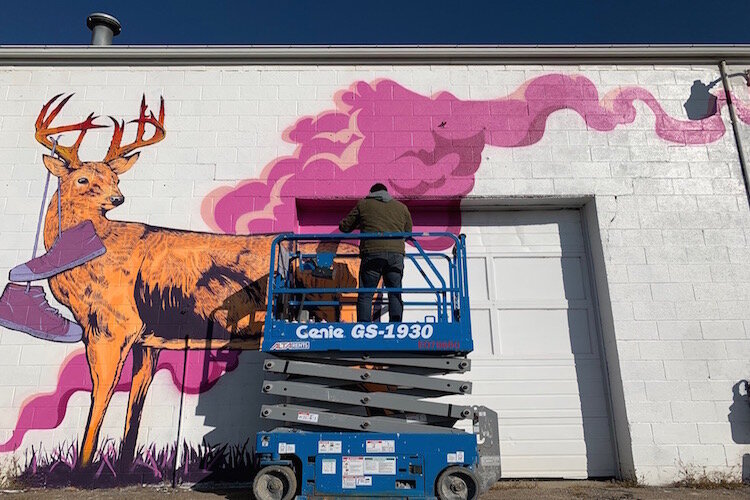 Nuri Mariela Ease paints his mural on Oakley Street for Flint's Free City Mural Festival.