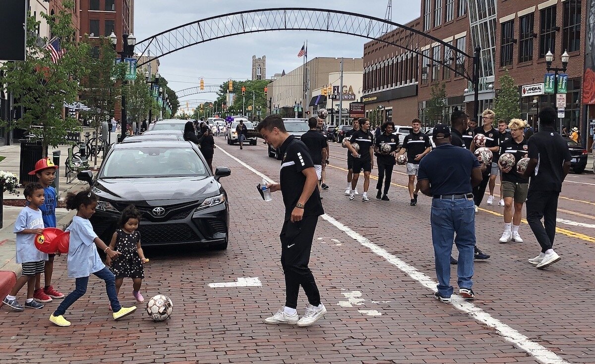 Flint City Bucks players kicked soccer balls with spectators during Flint's Juneteenth parade.